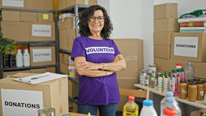 Middle age hispanic woman volunteer smiling confident standing with arms crossed gesture at charity...