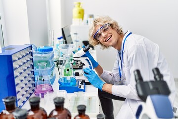 Young blond man scientist using microscope at laboratory