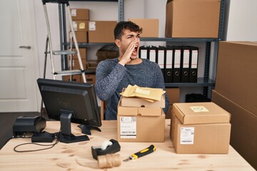 Young hispanic man working at small business ecommerce using smartphone looking confident with smile on face, pointing oneself with fingers proud and happy.