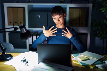 Young beautiful woman working at the office at night showing and pointing up with fingers number...