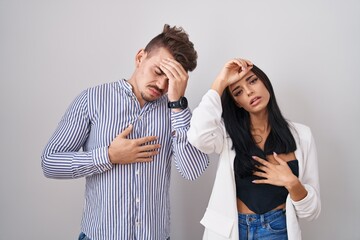 Young hispanic couple standing over white background touching forehead for illness and fever, flu and cold, virus sick