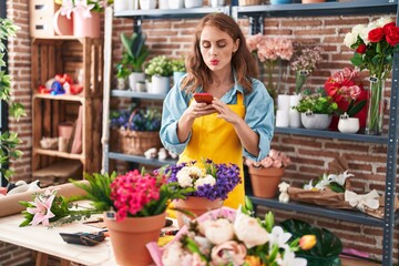Young beautiful hispanic woman florist make photo to plant by smartphone at florist