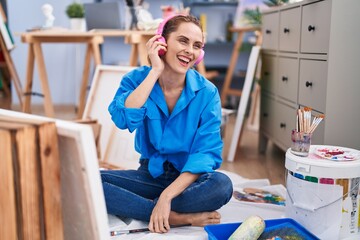 Young woman artist listening to music drawing at art studio