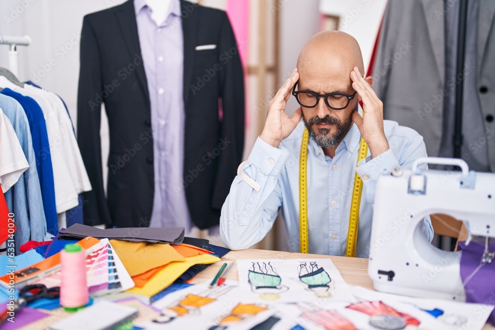 Poster Young bald man tailor stressed sitting on table at tailor shop