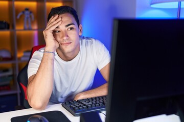 Young hispanic man streamer stressed using computer at gaming room