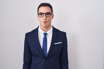 Young hispanic man wearing suit and tie making fish face with lips, crazy and comical gesture. funny expression.