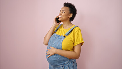 Young pregnant woman talking on smartphone smiling over isolated pink background