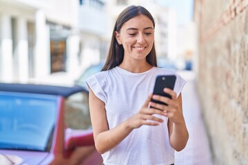 Fototapeta na wymiar Young beautiful hispanic woman smiling confident using smartphone at street