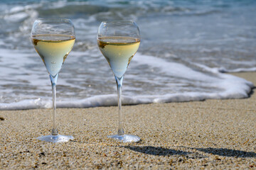 Summer time in Provence, two glasses of cold champagne cremant sparkling wine on sandy beach near Saint-Tropez in sunny day, Var department, France