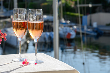 Summer party, drinking of French brut rose champagne sparkling wine in glasses in yacht harbour of...