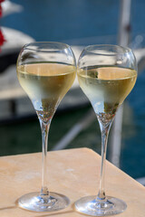 Drinking of French brut champagne sparkling wine in glasses, club party in yacht harbour of Port Grimaud near Saint-Tropez, French Riviera vacation, France