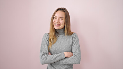 Young caucasian woman smiling confident standing with arms crossed gesture over isolated pink background