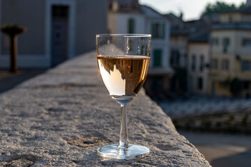French rose dry wine from Provence in glass in sunny day with view on old streets of Arles town in...