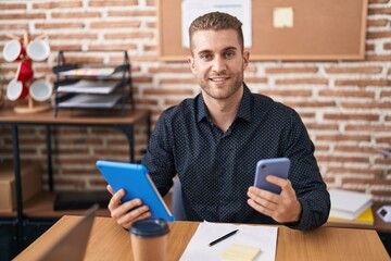 Young caucasian man business worker using smartphone and touchpad at office