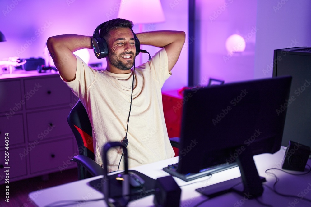 Canvas Prints young hispanic man streamer smiling confident relaxed with hands on head at gaming room