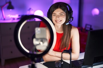 Young caucasian woman playing video games recording with smartphone looking positive and happy standing and smiling with a confident smile showing teeth