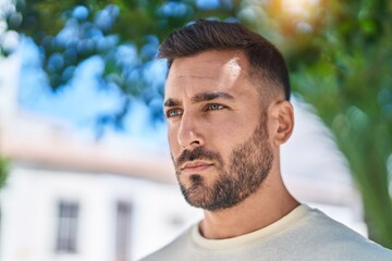 Fototapeta premium Young hispanic man looking to the side with serious expression at park