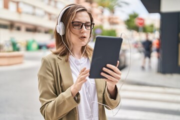 Fototapeta premium Young woman business worker using touchpad and headphones at street