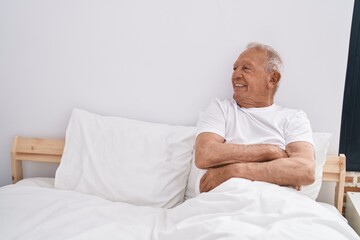 Senior grey-haired man smiling confident sitting on bed at bedroom