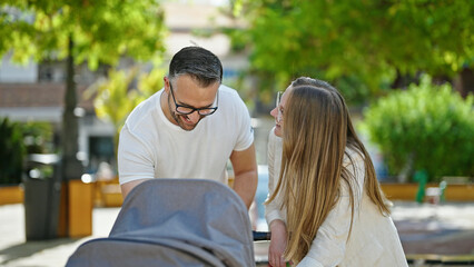 Family of three walking with a baby cart at the park
