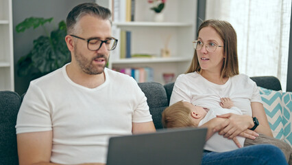 Fototapeta premium Family of mother, father and baby using laptop sitting on the sofa at home