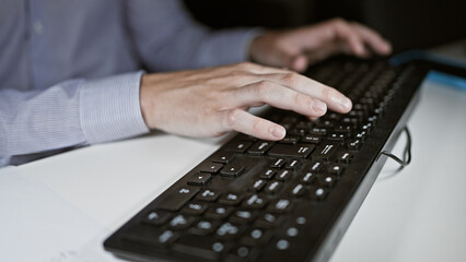 Young hispanic man using computer typing on keyboard at the office