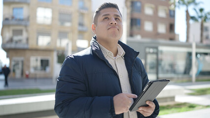 Young hispanic man using touchpad at street