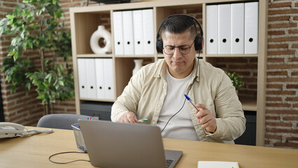 Young hispanic man business worker dancing using laptop at office