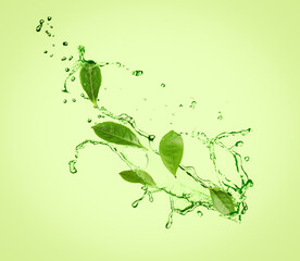 Fototapeta na wymiar Splashes of refreshing drink with leaves on pale green background. Green or matcha tea