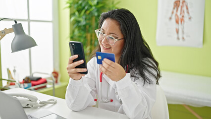 Young chinese woman doctor shopping with smartphone and credit card at the clinic