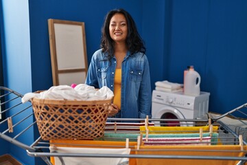 Young asian woman hanging clothes at clothesline winking looking at the camera with sexy...