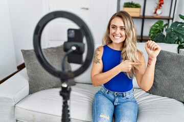 Young woman recording makeup tutorial by smartphone at home