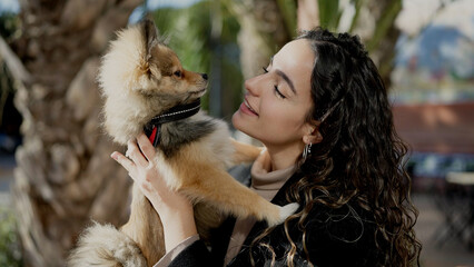 Young hispanic woman with dog smiling confident standing at park