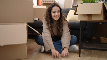 Young beautiful hispanic woman smiling confident sitting on floor at new home
