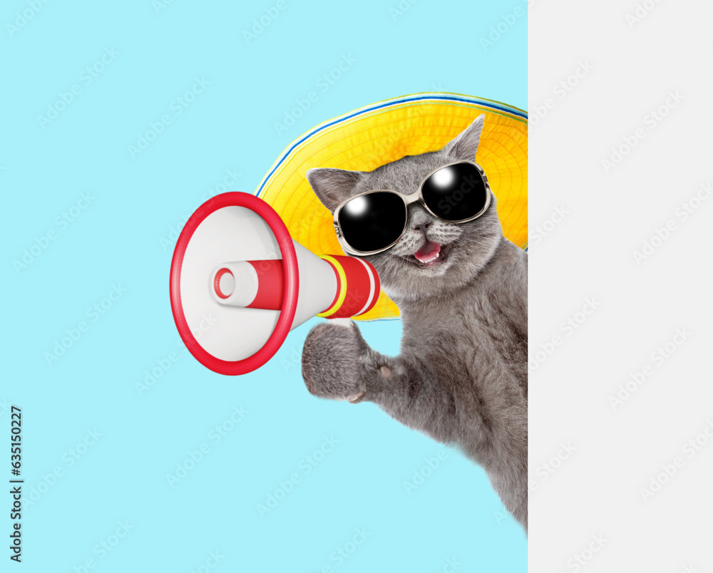 Poster happy cat wearing sunglasses and summer hat talks into megaphone and looks from behind empty white b