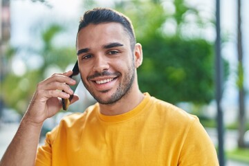 Young hispanic man smiling confident talking on the smartphone at street