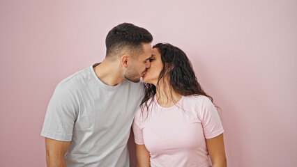 Man and woman couple smiling confident kissing over isolated pink background