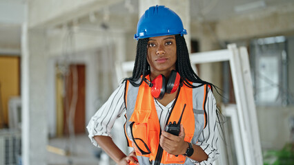 African american woman builder standing with relaxed expression at construction site