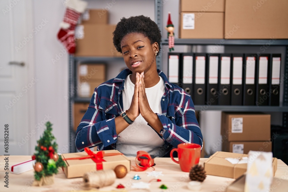 Canvas Prints African american woman working at small business doing christmas decoration begging and praying with hands together with hope expression on face very emotional and worried. begging.