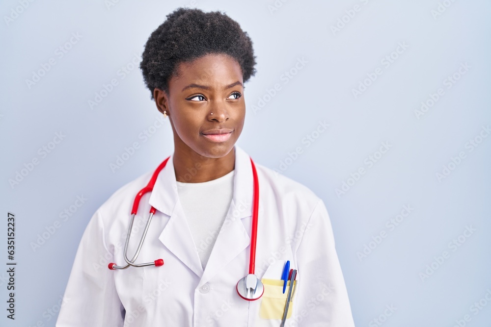 Canvas Prints African american woman wearing doctor uniform and stethoscope looking away to side with smile on face, natural expression. laughing confident.