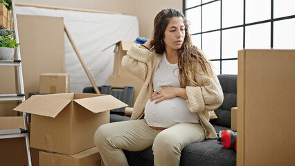 Young pregnant woman looking around with serious expression touching belly at new home