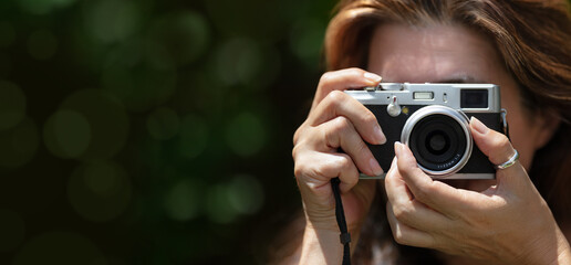 A woman taking pictures with a compact camera outdoors. Traveling and photographing concept.