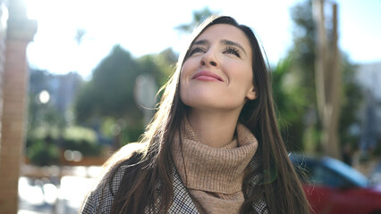 Beautiful hispanic woman smiling confident looking at the sky at street