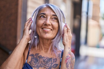 Middle age grey-haired woman smiling confident listening to music at street