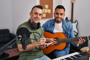 Two men musicians composing song playing classical guitar at music studio