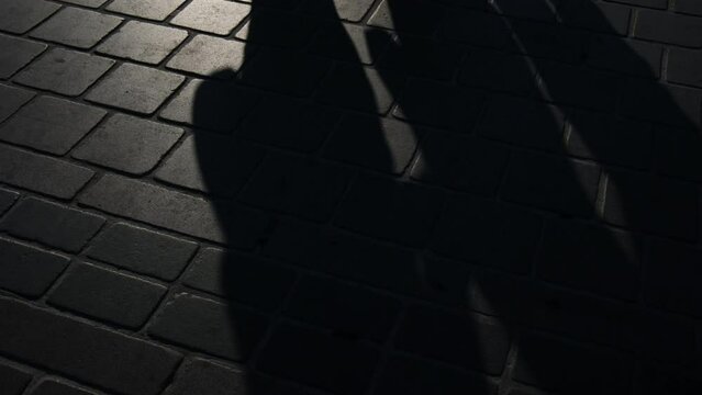 Shadows of walking people on the stone floor at street in slow motion