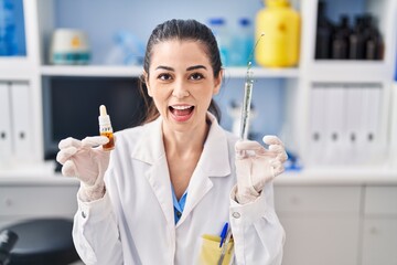 Young woman doing weed oil extraction at laboratory celebrating crazy and amazed for success with open eyes screaming excited.