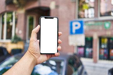 Man holding smartphone showing white blank screen at parking