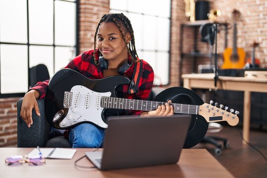 African american woman musician having online electrical guitar lesson at music studio