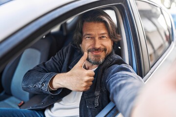 Middle age man make selfie by camera doing ok gesture at street